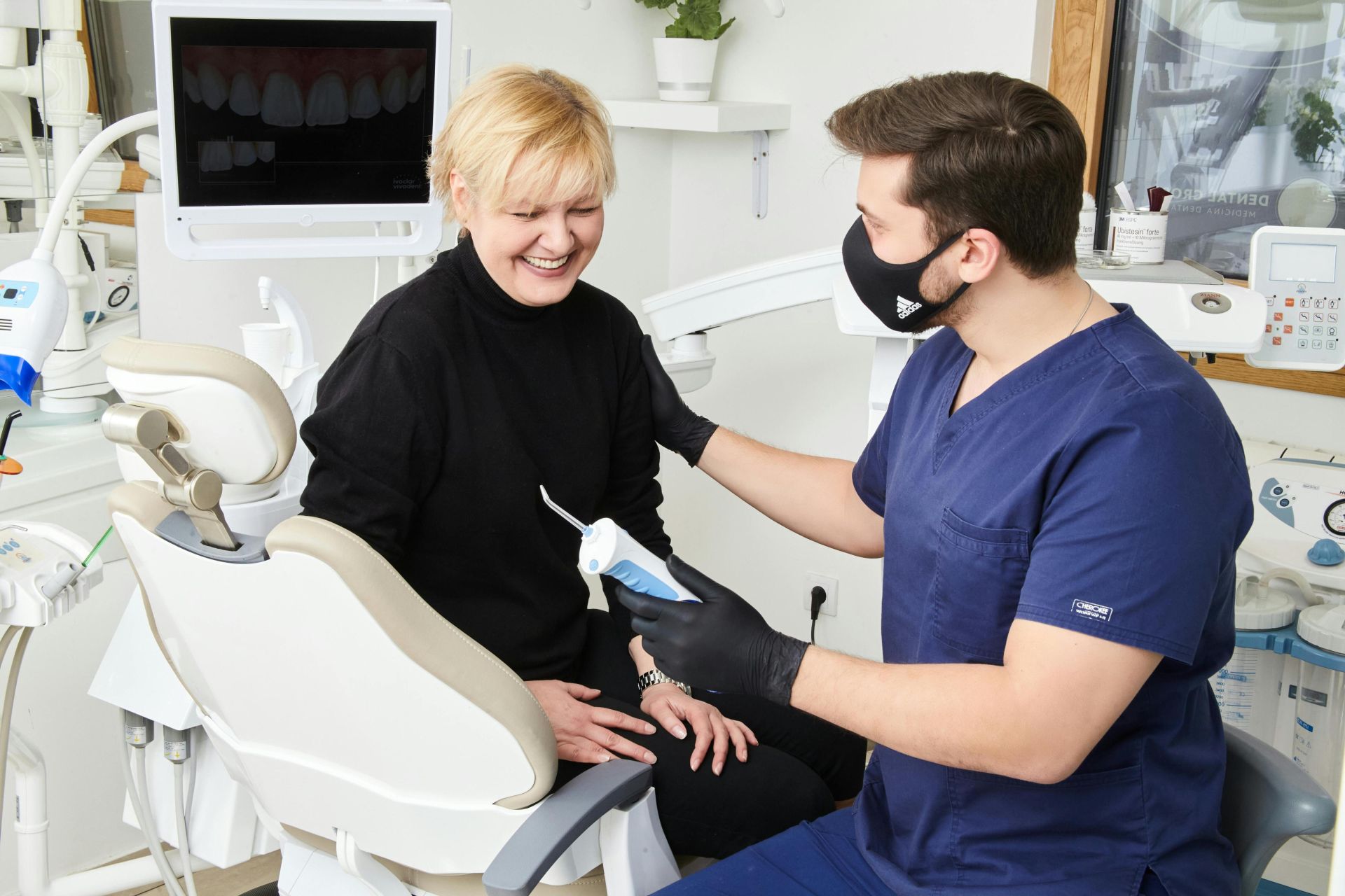 A dentist in Belgrade offers a friendly consultation to a smiling patient in a modern clinic.